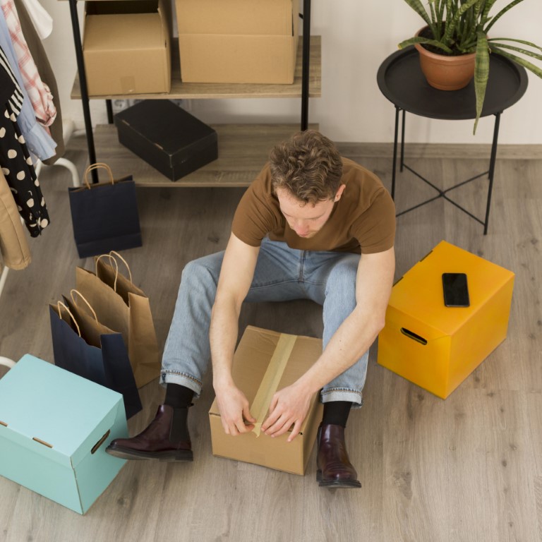 homem com caixa de produtos de compra internacional verificando se tem taxas abusivas compra pela internet
